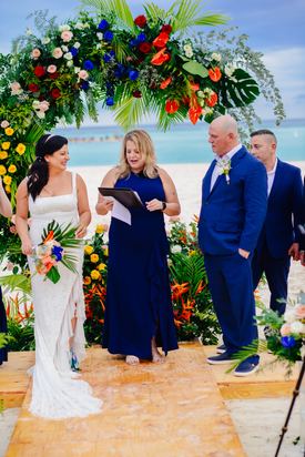 Novia y novio sonriendo durante una colorida ceremonia de boda en la playa de Punta Cana