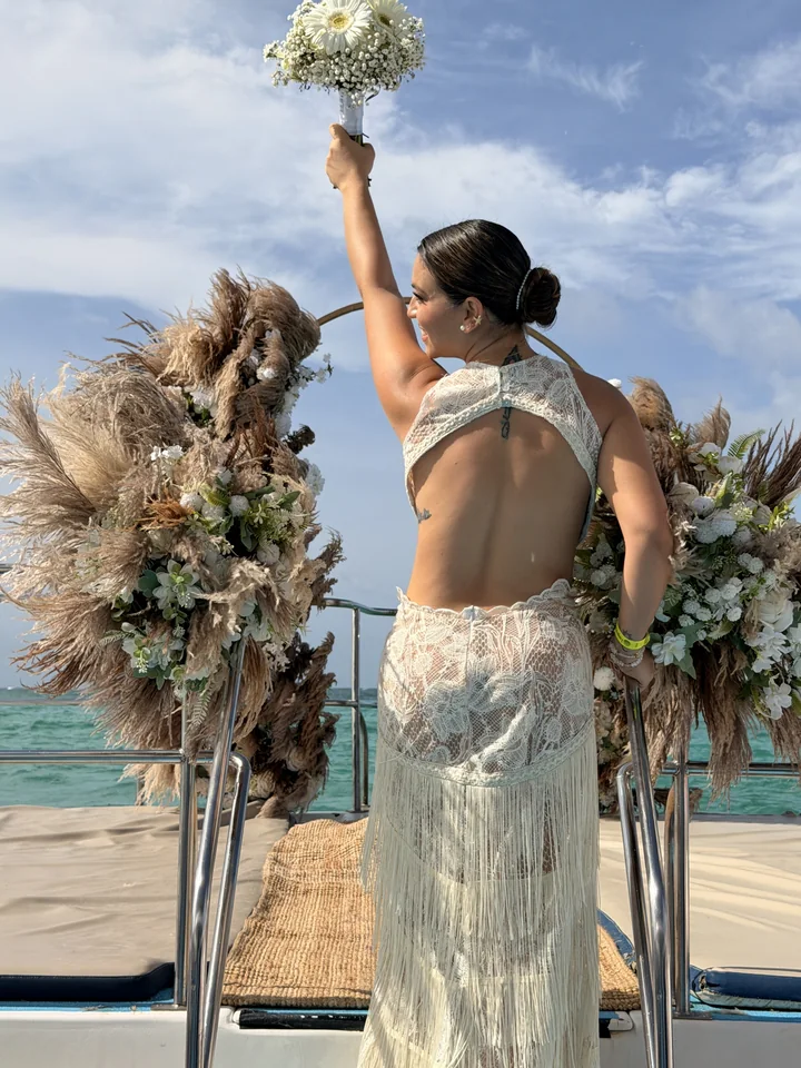 Novia celebrando junto a un arco floral con pampas a bordo de un catamarán en Punta Cana