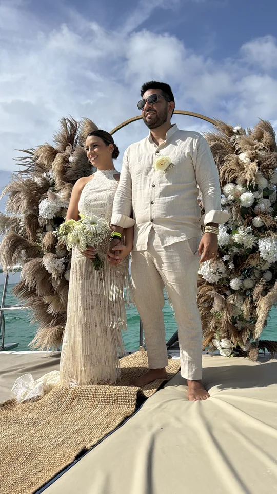 Pareja de elopement bajo un arco con pampas en un catamarán privado de Punta Cana