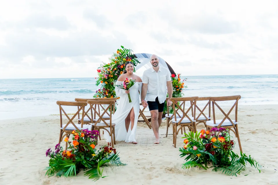 Recién casados caminando por una colorida ceremonia tropical de elopement en la playa