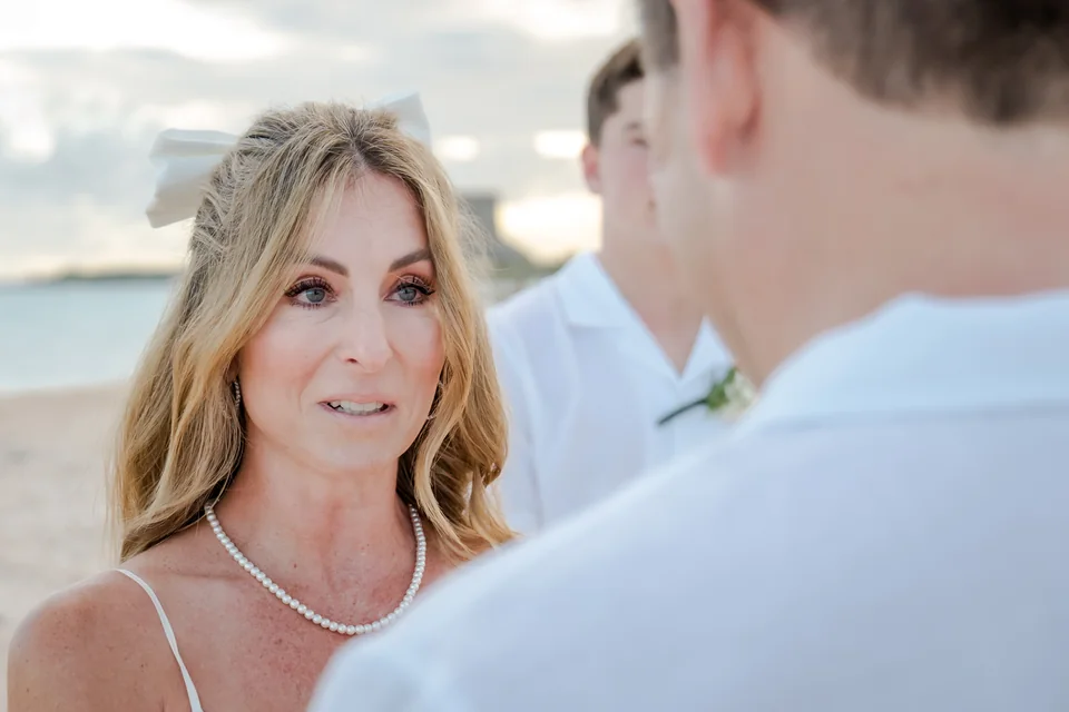 Novia escuchando los votos de su pareja durante un elopement en una playa de Punta Cana