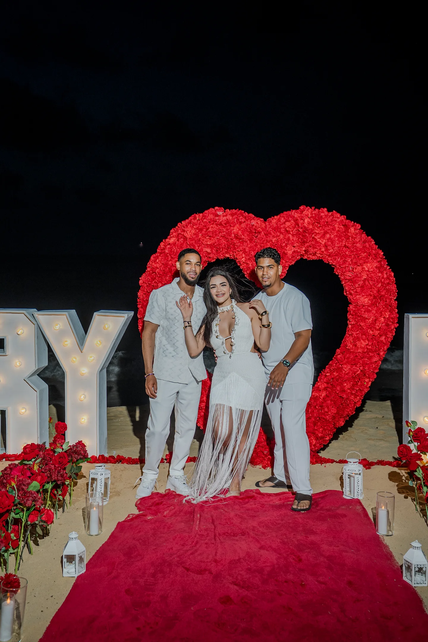 Pareja y coordinadora junto a un montaje de propuesta con corazón en la playa